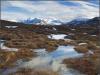 Distant mountains across a snowy bog.